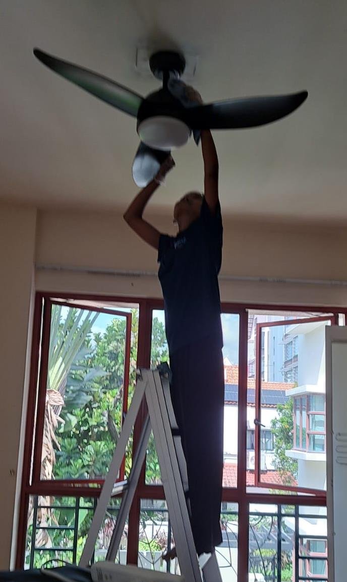 ACM crew member servicing a ceiling fan on-site